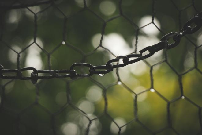 A photograph of a chain against a green background
with water dripping from it.
